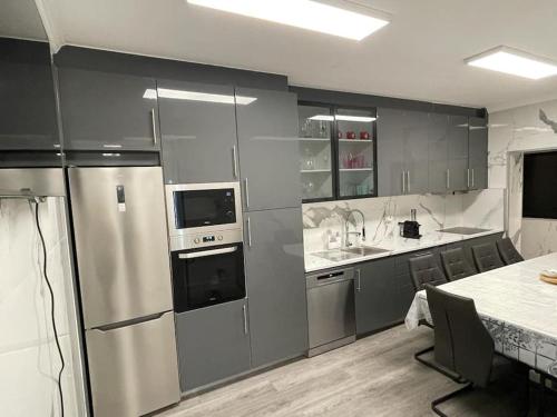 a kitchen with stainless steel appliances and gray cabinets at Coração de Furadouro in Ovar