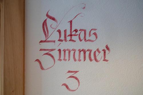 a sign with red writing on the side of a wall at FP Muehlmann&Schoen in Innervillgraten