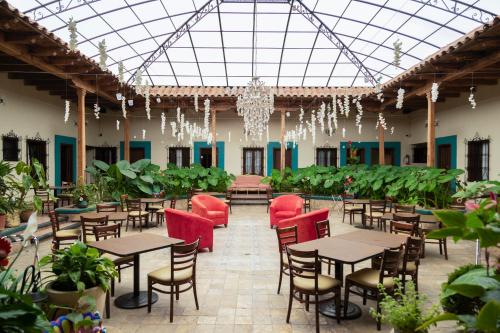 un restaurante con mesas, sillas y plantas en Gran Hotel El Encanto en San Cristóbal de Las Casas