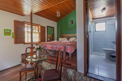 1 dormitorio con cama, mesa y baño en Pousada Vila do Campo, en Lavras Novas