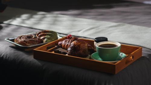 a tray of pastries and a cup of coffee on a bed at Hotel Brecha in Tijuana