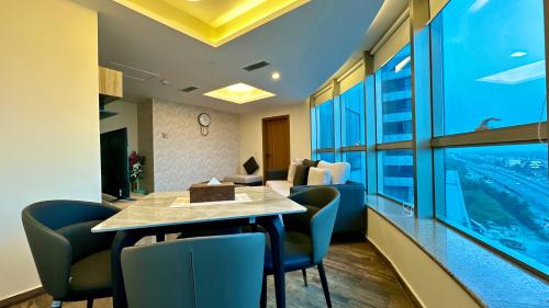 ein Hotelzimmer mit einem Tisch, Stühlen und einem Fenster in der Unterkunft Centaurus Apartment One Bed in Islamabad