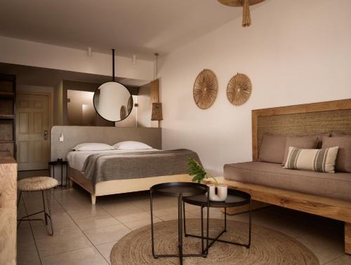 a bedroom with a bed and a couch and a mirror at Seaside A Lifestyle Resort - Adults Only in Agia Pelagia