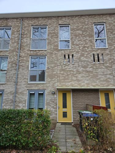 a brick building with a yellow door and windows at Residence Dordrecht in Dordrecht