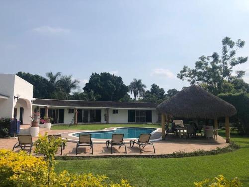 un patio trasero con piscina, sillas y cenador en Quinta Los Soles, en Yautepec