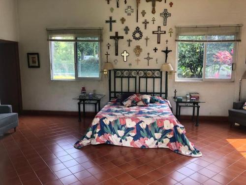 1 dormitorio con 1 cama y cruces en la pared en Quinta Los Soles, en Yautepec