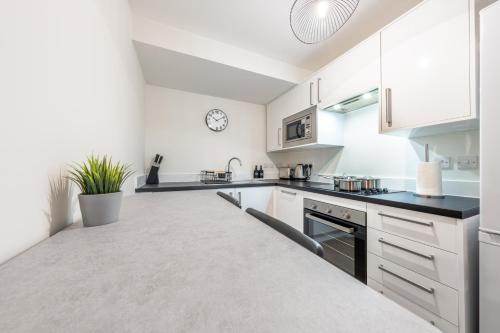 a kitchen with white cabinets and black counter tops at Telford House in Luton
