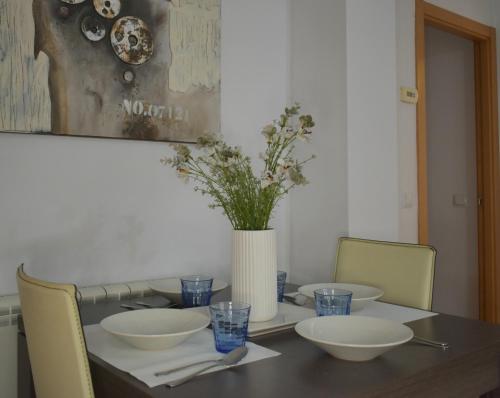 Una mesa de comedor con sillas y un jarrón con flores. en Apartamento Vive Teruel, en Teruel