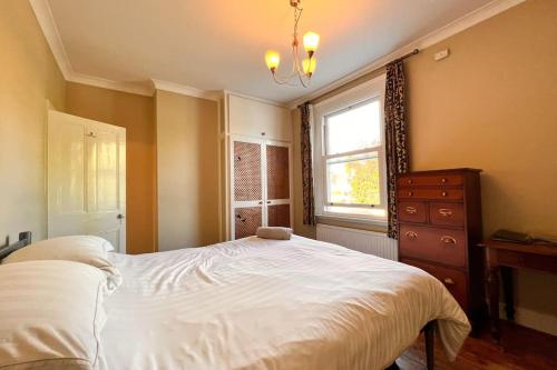 1 dormitorio con 1 cama, vestidor y ventana en Two Bedroom Period Property in Tivoli Cheltenham, en Cheltenham