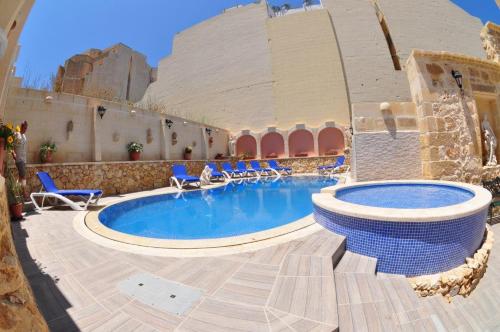 un resort con piscina, sedie e un edificio di 6 Bedroom Farmhouse with Private Pool in Zebbug Gozo a Żebbuġ