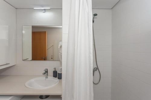 Baño blanco con lavabo y espejo en Sa Perdiu 14, en Cala Santandria
