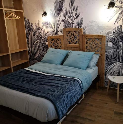 Cette chambre comprend un lit avec des draps bleus et un mur orné de plantes. dans l'établissement cottage du Fort Ambleteuse, à Ambleteuse