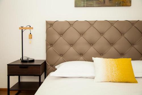 a bed with a brown headboard and a yellow pillow at Guesthouse Smart Rooms Bucharest in Bucharest