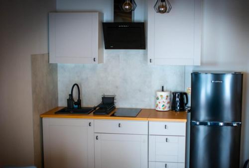 a kitchen with a stainless steel refrigerator and white cabinets at Widokowe Stodoły in Chyszówki