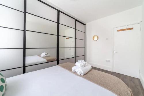 a bedroom with two white beds and mirrors at Central Ground Floor Flat Free Parking in London