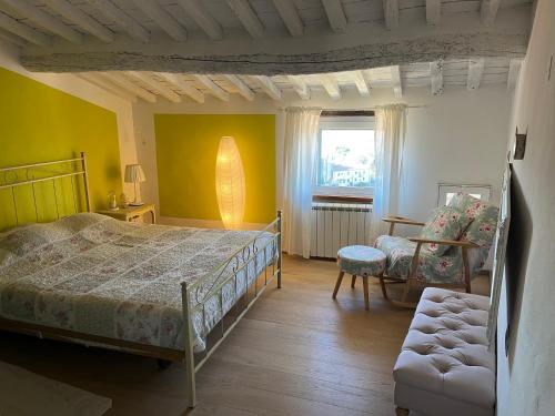 een slaapkamer met een bed, een stoel en een raam bij Rifugio Romantico in Castagneto Carducci
