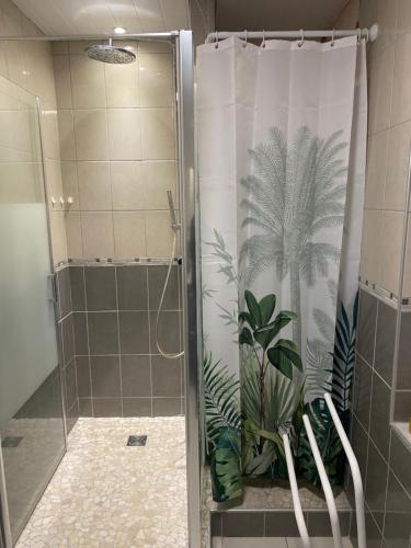 een badkamer met een douche en een douchegordijn met planten bij Maison avec piscine in Saint-Pierre-de-Boeuf