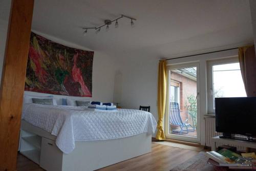 a white bedroom with a bed and a sliding glass door at Gästewohnung von J&O am Fluss. in Jork