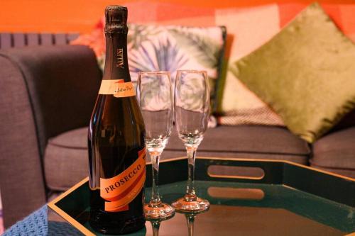 a bottle of champagne and two wine glasses on a table at Glen Getaway - (Luxury Pod) in Stranraer