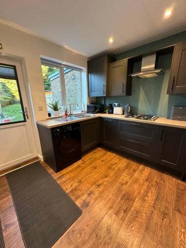 a kitchen with black cabinets and a wooden floor at Elwood - spacious contemporary home from home in Harrogate with parking in Harrogate