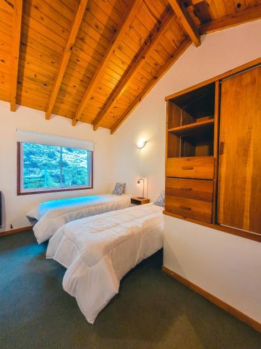 two beds in a bedroom with a large window at Cabaña Oasis in San Martín de los Andes