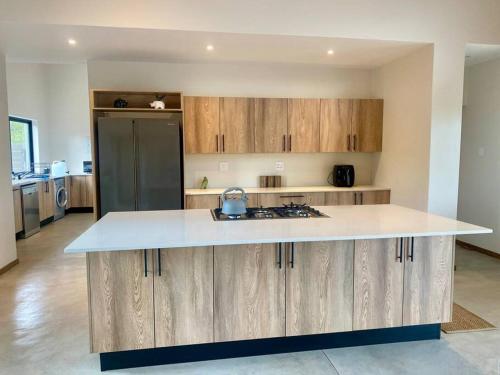 a kitchen with a white counter top and wooden cabinets at Corkwood Villa in Hoedspruit