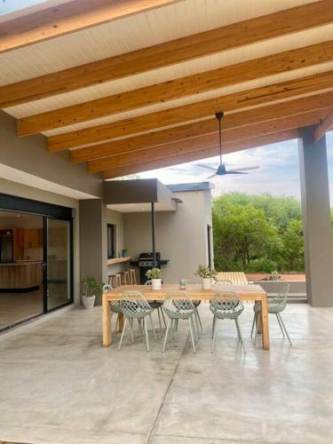 a patio with a wooden table and chairs and a dining room at Corkwood Villa in Hoedspruit