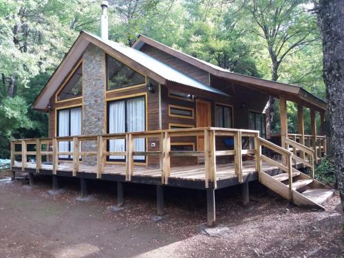 a cabin in the woods with a large deck at Complejo Alto La Invernada in Las Trancas