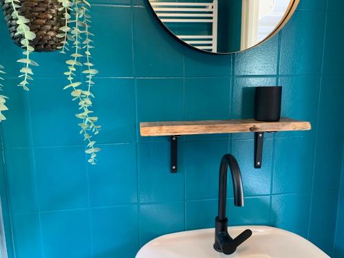 baño con paredes azules, lavabo y espejo en NEW: recent opgeknapte houten chalet - de Veluwe, en Nunspeet