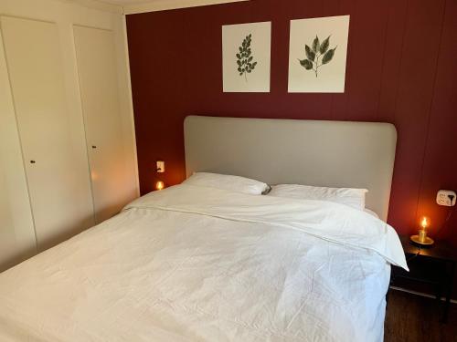 1 dormitorio con 1 cama blanca y 2 cuadros en la pared en NEW: recent opgeknapte houten chalet - de Veluwe, en Nunspeet