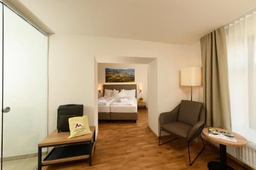 um quarto de hotel com uma cama e uma cadeira em Heilmoorbad Schwanberg em Schwanberg