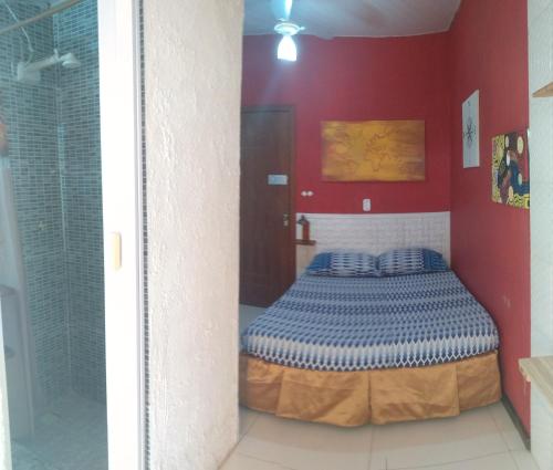 1 dormitorio con 1 cama en una pared roja en Odoya Guest House, en Salvador