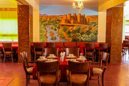 una sala da pranzo con tavolo, sedie e murale di ROSE M'GOUNA a El Kelaa des Mgouna