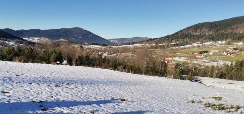 a snow covered hill with a village in the distance at Widokowe Stodoły in Chyszówki
