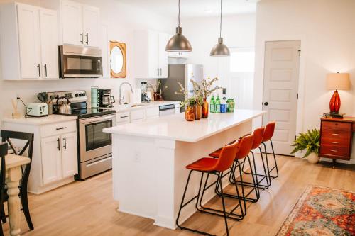 a kitchen with white cabinets and a large island with bar stools at Artist Retreat Near Downtown, Stadium & UGA in Athens