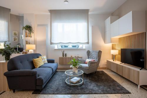 a living room with a blue couch and a tv at TRENTINO LODGE Piazza Municipio in Strigno