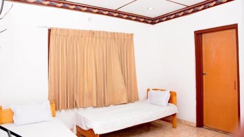 um quarto com duas camas e uma janela em New AT hotel em Jaffna