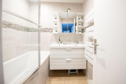 uma casa de banho branca com uma banheira e um lavatório em ELISE DE ROCHE Équipé Balcon Parking RER B em Le Bourget