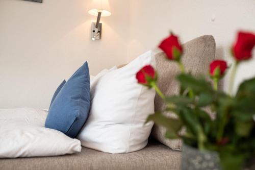 eine Couch mit Kissen und eine Vase mit roten Rosen in der Unterkunft Haus Ankerlicht 1.OG Wohnung 66 in Westerland