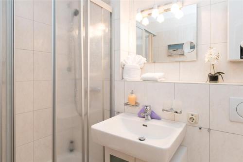 ein weißes Bad mit einem Waschbecken und einer Dusche in der Unterkunft Haus Ankerlicht 1.OG Wohnung 66 in Westerland