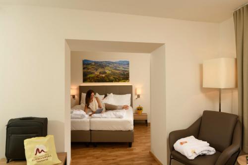 a woman sitting on a bed in a hotel room at Heilmoorbad Schwanberg in Schwanberg