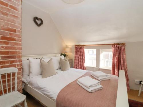 a bedroom with a white bed with towels on it at Rosemary Cottage, Aldeburgh in Aldeburgh