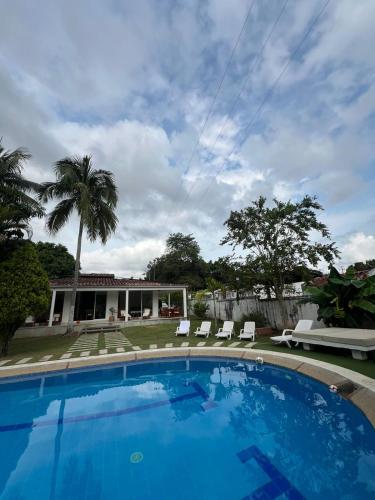 a swimming pool with chairs and a house at Villa Tarek in Carmen de Apicalá