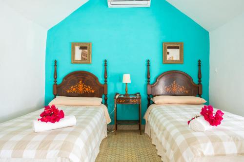 two beds in a room with blue walls and red flowers at XPCE Casería San José in Bobadilla