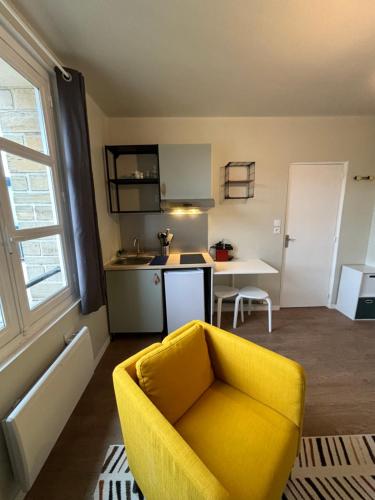 a living room with a yellow chair and a kitchen at Appart du Théâtre in Caen