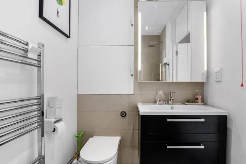 a bathroom with a sink and a toilet and a mirror at Luxury modern flat near ExCel, 02 & Canary Wharf in London