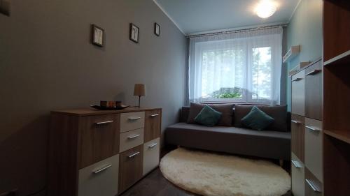 Dormitorio pequeño con banco y ventana en APARTAMENT SŁUPSK, en Słupsk