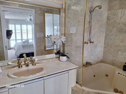 uma casa de banho com um lavatório, uma banheira e um espelho. em Isle of Palms 112 em Gold Coast