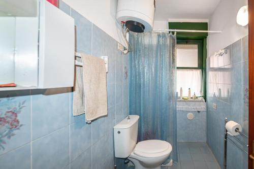 y baño azul con aseo y ducha. en Casa Jaya Taormina en Schisò