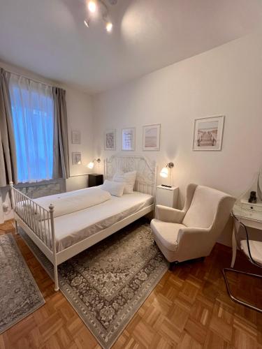 biała sypialnia z łóżkiem i krzesłem w obiekcie Apartment Blick ins Grüne w mieście Bamberg